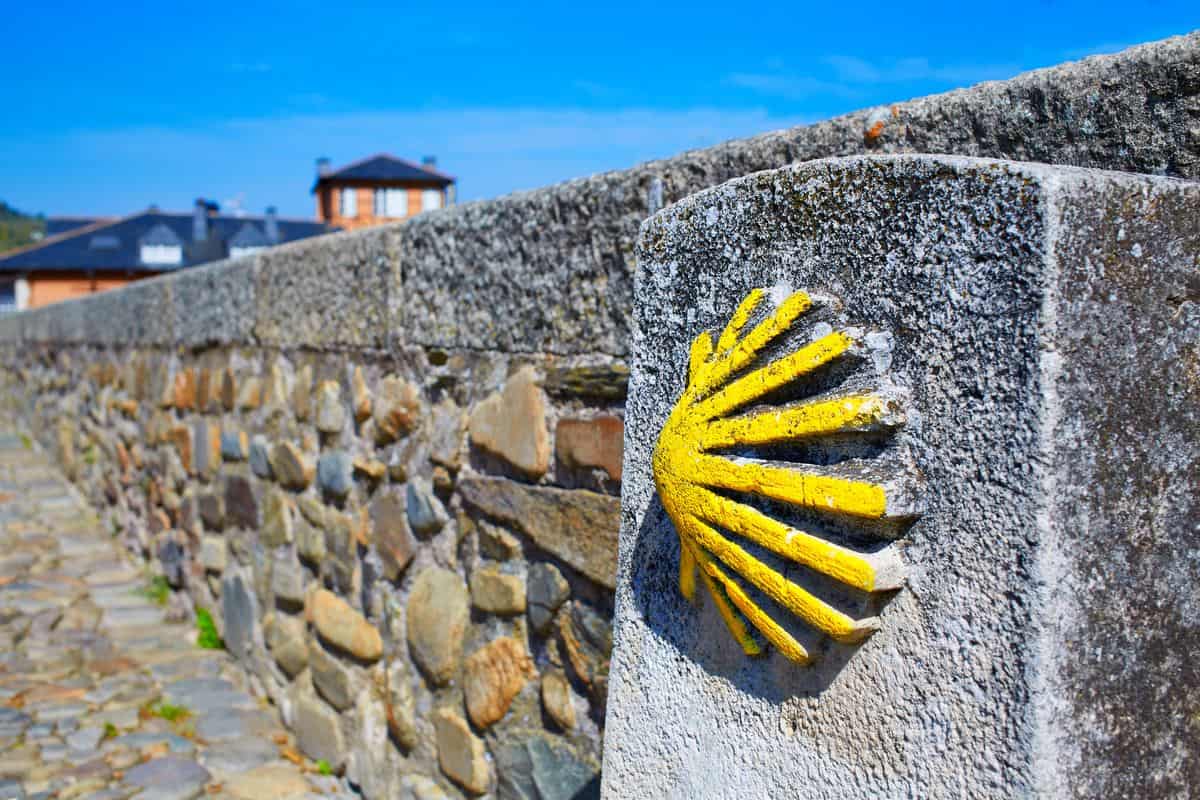 Spanien-Reise-Tipps – Steinmauer in El Bierzo mit gelber Muschel, das Zeichen für den Jakobsweg