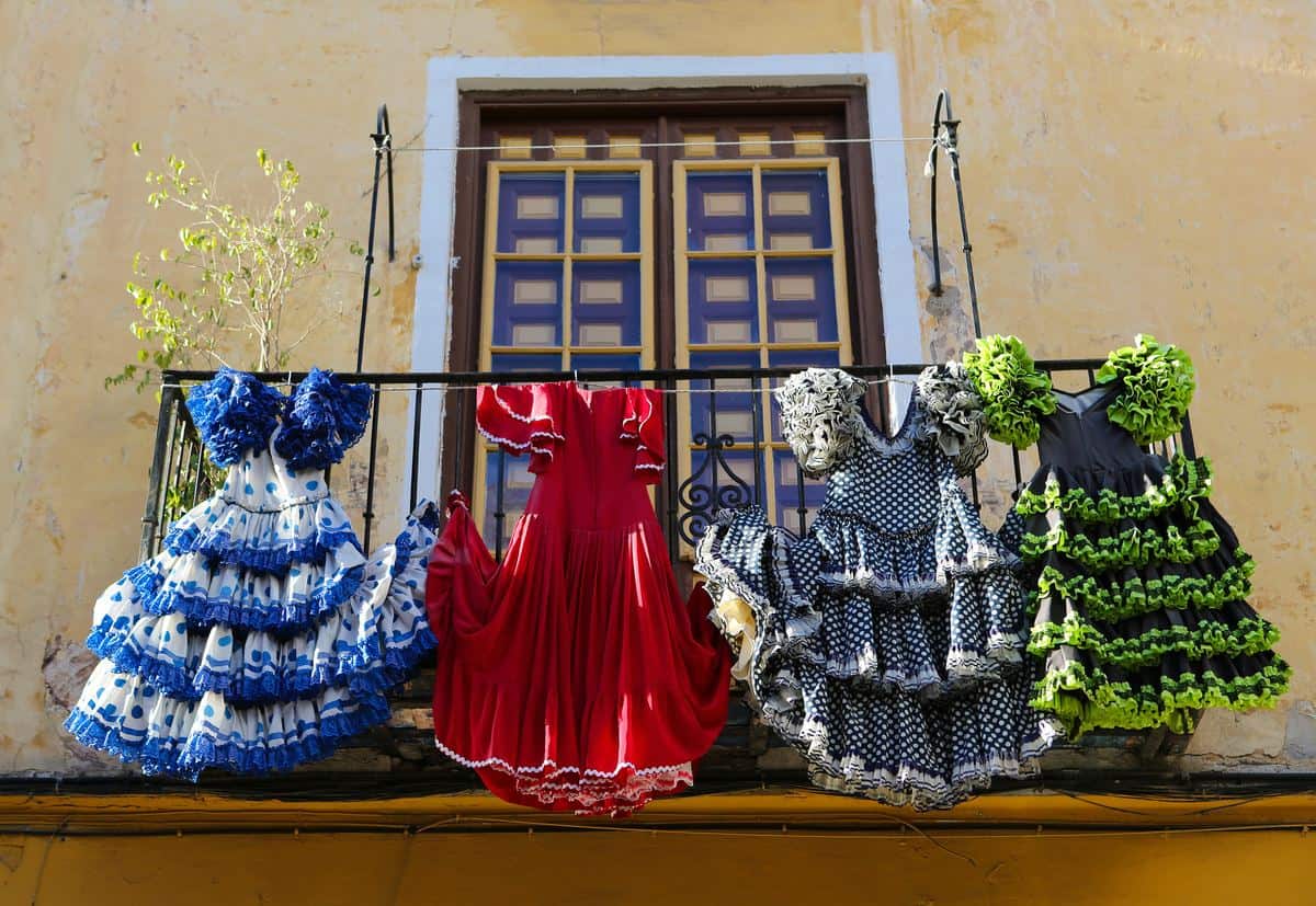 Spanien-Reise-Tipps – Balkon in Malaga, Andalusien, vor dem eine Wäscheleine gespannt ist und auf der mehrere Flamenco-Kleider hängen